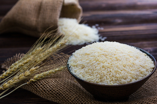 White rice and ear of paddy on wooden table.