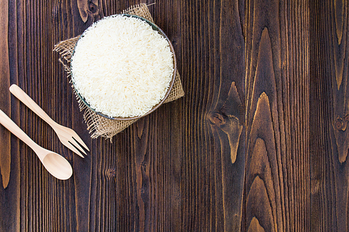 White rice and wooden spoon and fork on wooden table