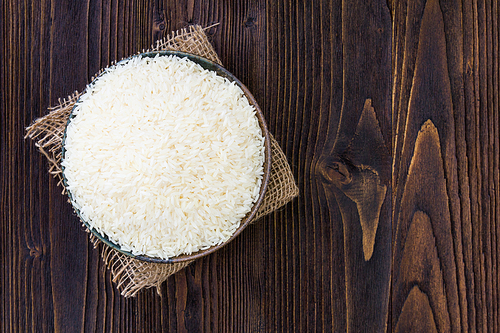 White rice in bowl on wooden table.