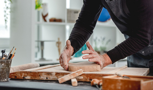 Man working with clay on wooden board at pottery workshop