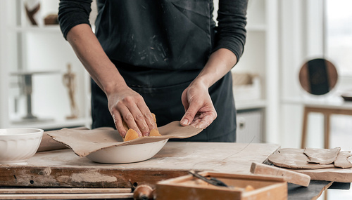 Woman forming future plate using mold at pottery workshop