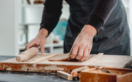 Man using rolling pin on clay at pottery workshop