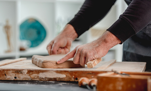 Man working with clay on wooden board at pottery workshop