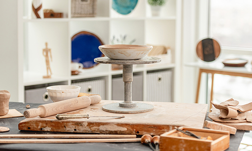 Potter's wheel and pottery tools on table at workshop