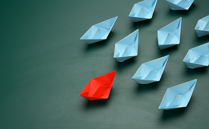 group of paper boats on a green background. concept of a strong leader in a team, manipulation of the masses, following new perspectives, collaboration and unification. Startup