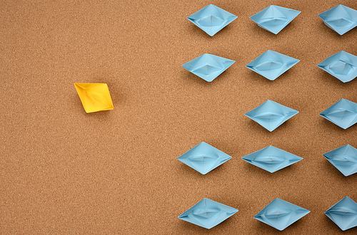 group of paper boats on a brown background. concept of a strong leader in a team, manipulation of the masses, following new perspectives, collaboration and unification. Startup