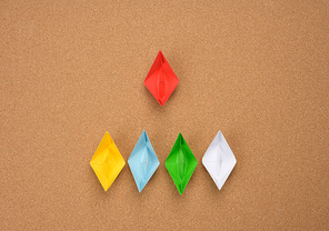 group of paper boats and one red on abrown background. The concept of a strong leader, manipulation of the masses, a close-knit team and effective management