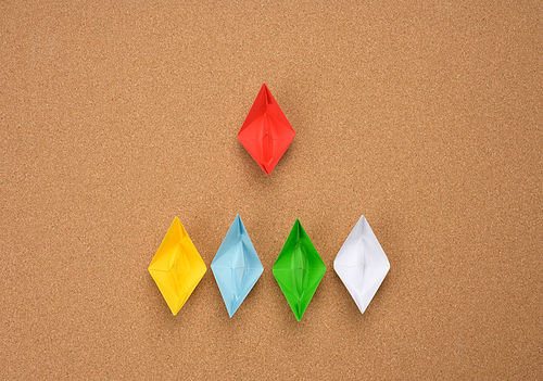 group of paper boats and one red on abrown background. The concept of a strong leader, manipulation of the masses, a close-knit team and effective management