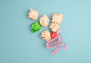 miniature metal cart with mint paper balls on a blue background. Concept for buying ideas, new creative brainstorming, flat lay