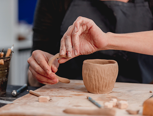 Hands of woman potter forming cup from clay
