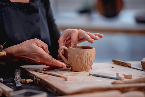 Hands of woman potter forming cup from clay