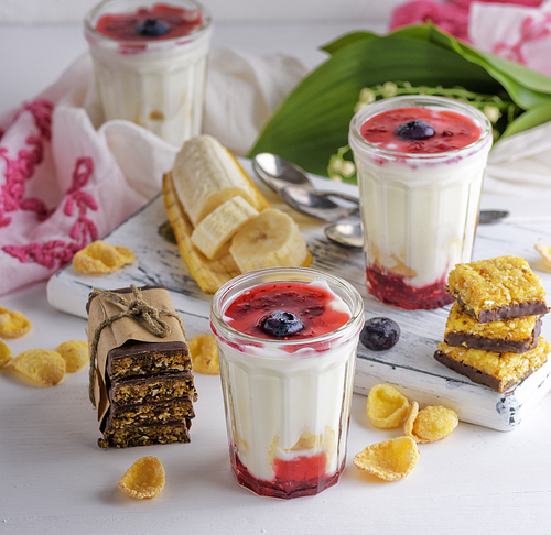 yogurt in transparent glass with syrup and banana on a white wooden background