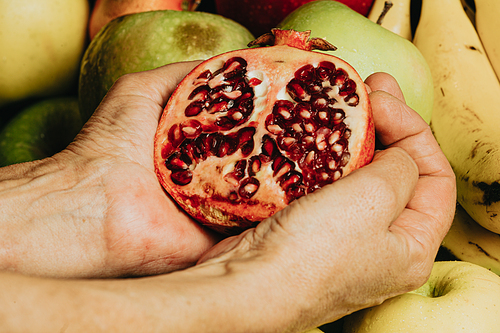 Old hands grabbing a passion fruit over a full of fruits background with water drops over the apple, healthy concept shot