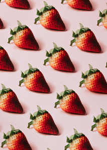 Minimal and repetitive pattern of delicious strawberries over a pastel pink background