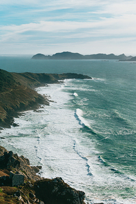 An aerial shot of a massive wild coast in spain with the waves crashing against it