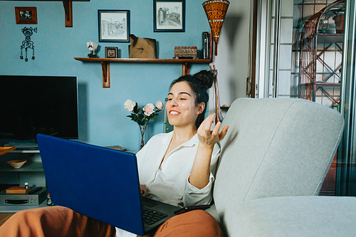 A woman smiling while making an office video call from home with the computer