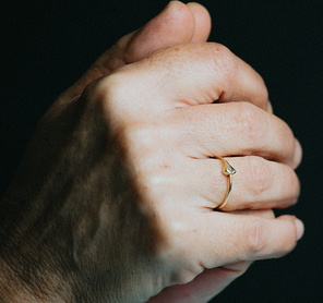A pair of old hands praying with a luminous ring on the finger, jewelry concept shot