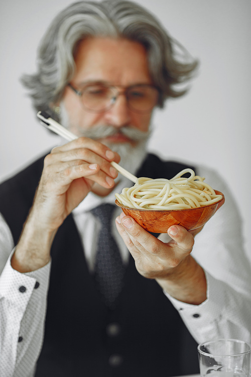 Lunch break. Elegant man in office. Businessman in white shirt. Man eats noodles.
