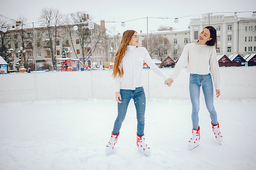 Girls in a winter city. Beautiful ladies in a white sweater. Women in a ice arena