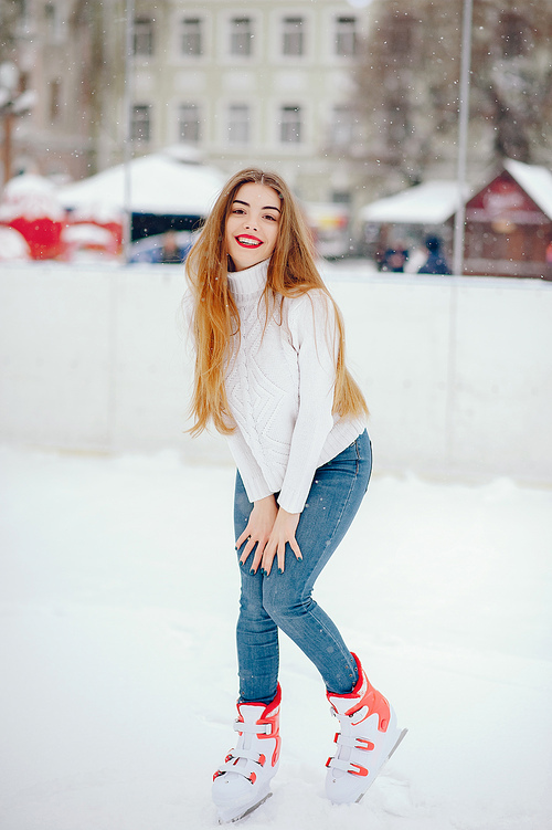 Girl in a winter city. Beautiful lady in a white sweater. Woman in a ice arena