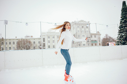 Girl in a winter city. Beautiful lady in a white sweater. Woman in a ice arena