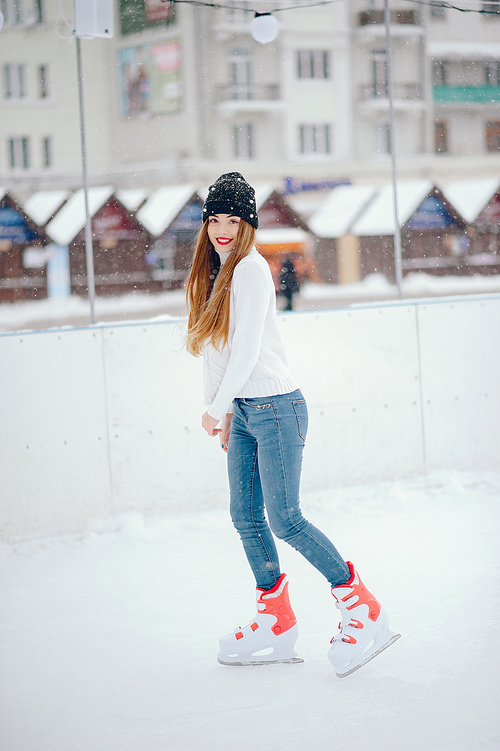 Girl in a winter city. Beautiful lady in a white sweater. Woman in a ice arena