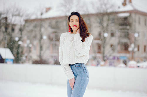 Cute girl standing in a winter city. Woman in a white sweater.