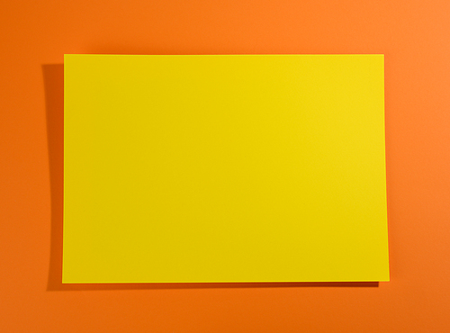 blank yellow sheet of paper on orange background with shadow, abstract backdrop for inscription, copy space