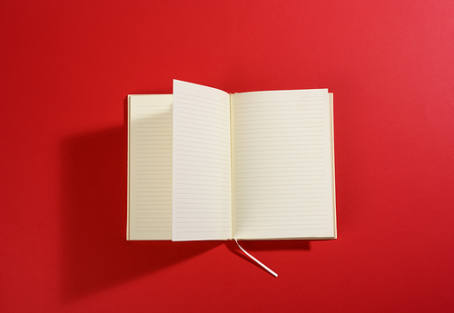 open notebook with blank white sheets on red background, top view