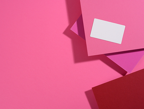 blank rectangular business card lies on a modern pink background sheets of paper with a shadow. Business template, flat lay