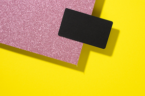 blank black rectangular business card on a creative background from sheets of paper with shadow, yellow sheets, flat lay