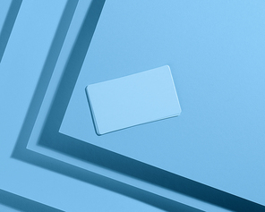 blank  rectangular business card on creative blue background from sheets of paper with shadow, top view