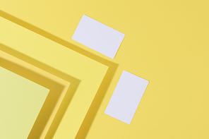 blank white rectangular business card on creative yellow background from sheets of paper with shadow, top view