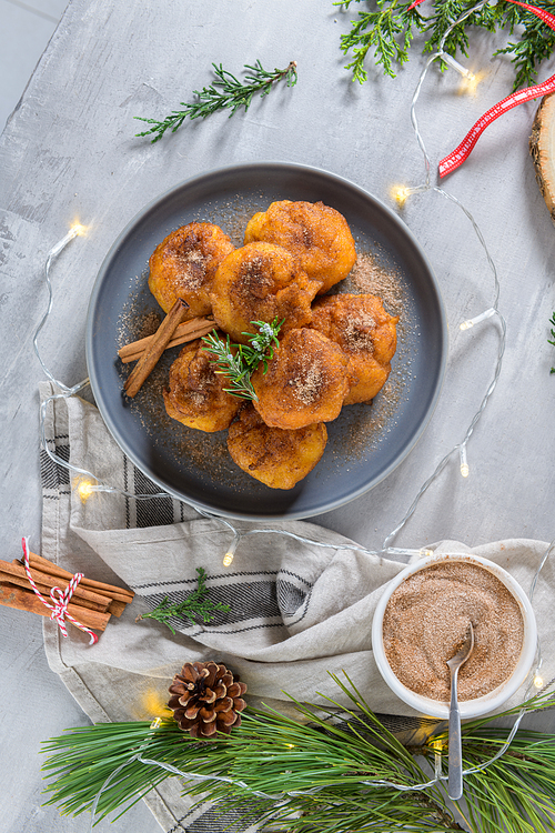 Traditional portuguese Christmas sweets Sonhos with sugar and cinnamon on kitchen countertop.