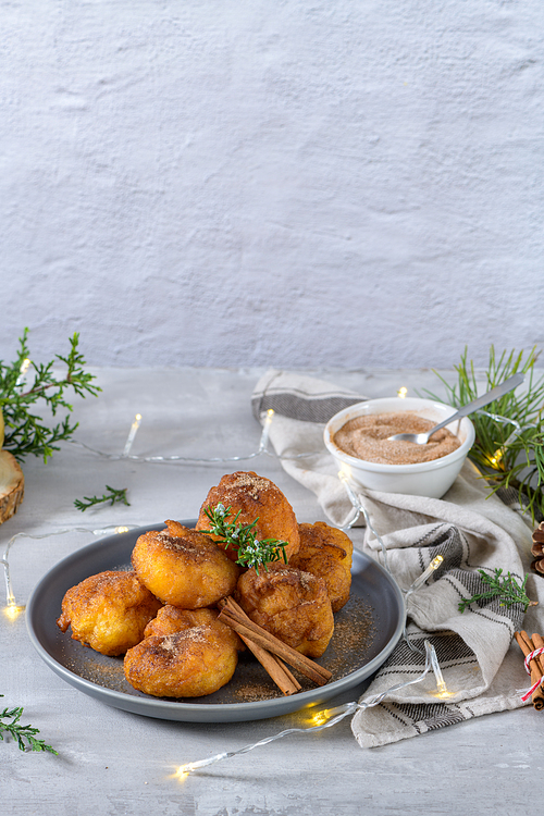 Traditional portuguese Christmas sweets Sonhos with sugar and cinnamon on kitchen countertop.