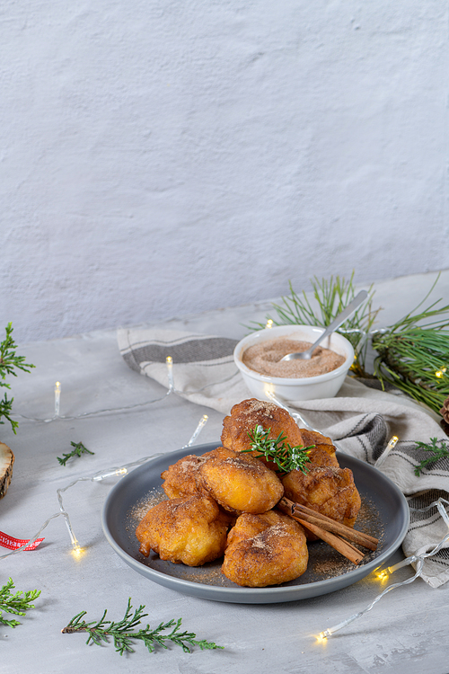 Traditional portuguese Christmas sweets Sonhos with sugar and cinnamon on kitchen countertop.