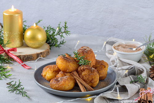 Traditional portuguese Christmas sweets Sonhos with sugar and cinnamon on kitchen countertop.