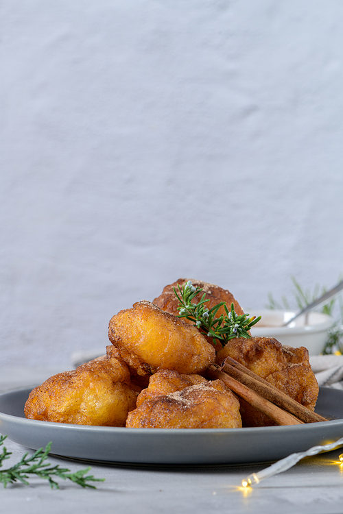 Traditional portuguese Christmas sweets Sonhos with sugar and cinnamon on kitchen countertop.