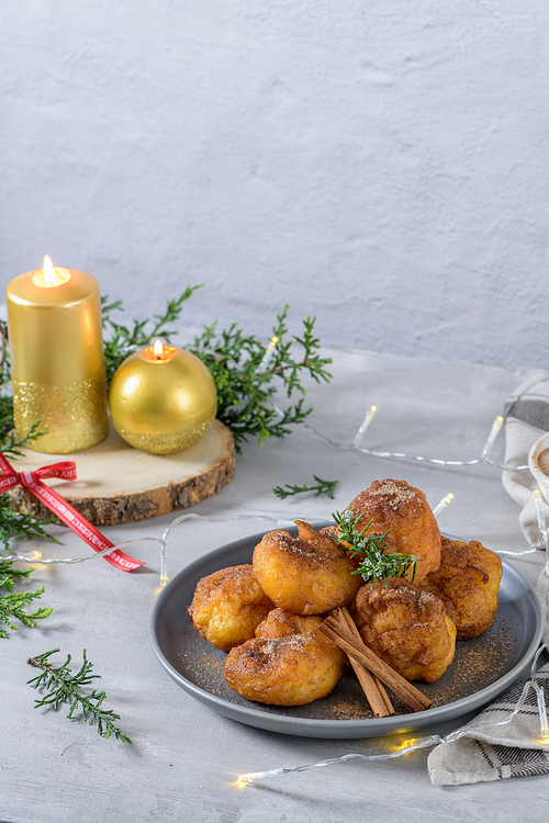 Traditional portuguese Christmas sweets Sonhos with sugar and cinnamon on kitchen countertop.