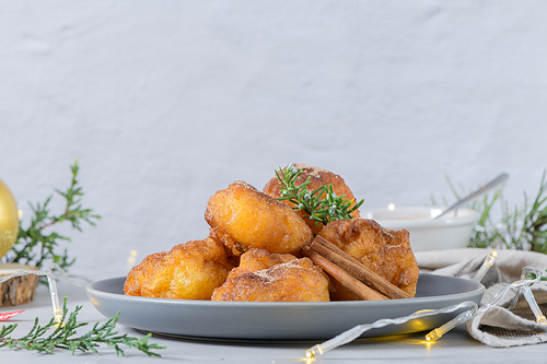 Traditional portuguese Christmas sweets Sonhos with sugar and cinnamon on kitchen countertop.