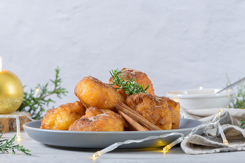 Traditional portuguese Christmas sweets Sonhos with sugar and cinnamon on kitchen countertop.