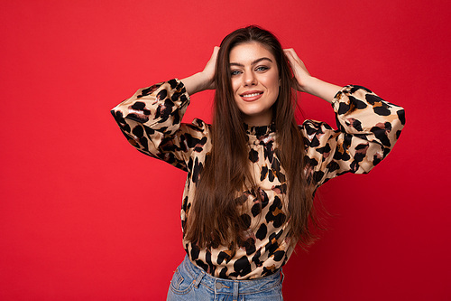 Photo of young happy smiling beautiful fashionable sexy brunette woman wearing stylish leopard blouse isolated on red background with empty space.