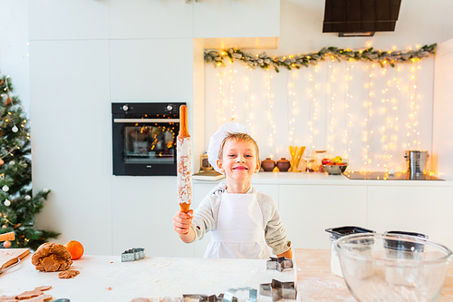 Cute little boy making gingerbread, cutting cookies of gingerbread dough. Christmas bakery. Festive food, cooking process, family culinary, Christmas and New Year traditions concept