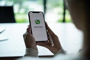 CHIANG MAI, THAILAND - JULY 15 2021 : Man holding a iPhone and open appstore searching social Internet service WhatsApp on the screen. iPhone 6s was created and developed by the Apple inc.