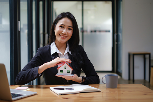 A real estate agent demonstrates the House model to clients interested in purchasing house insurance. The concept of home insurance and property.