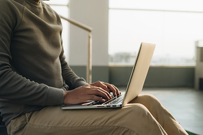 a businessman sitting with the laptop on his knees.