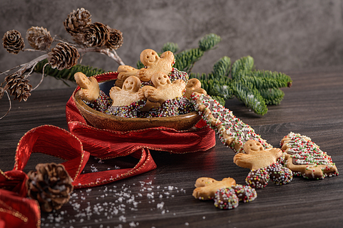 Christmas holiday background with gingerbread cookies, candy canes and evergreens over wooden table. Christmas and New year food. Christmas decoration and sweets on wood background.