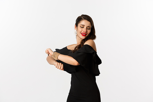 Fashion and beauty. Attractive woman feeling happy and dancing in black party dress, standing carefree against white background.