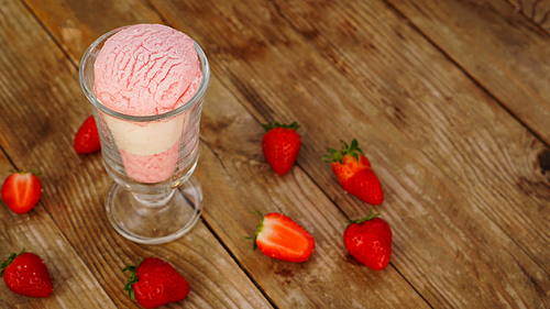 Strawberry and vanilla ice cream in a glass glass. Strawberries on wooden background