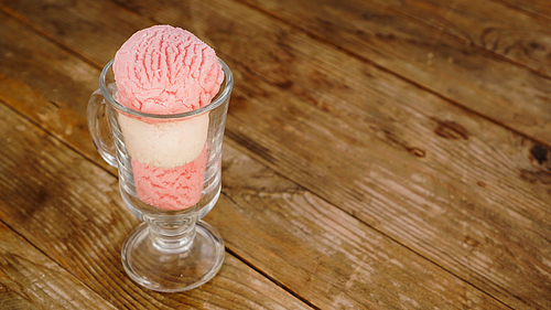Strawberry and vanilla ice cream in a glass glass on wooden background